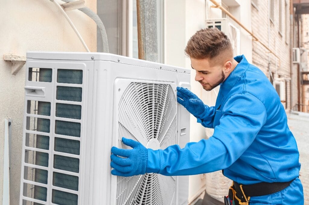 Technician servicing an outdoor air conditioning unit