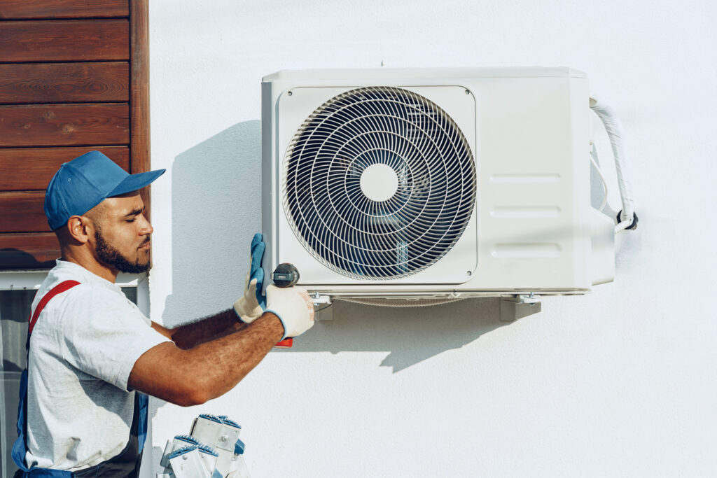 Technician installing a new air conditioning unit on the side of a home
