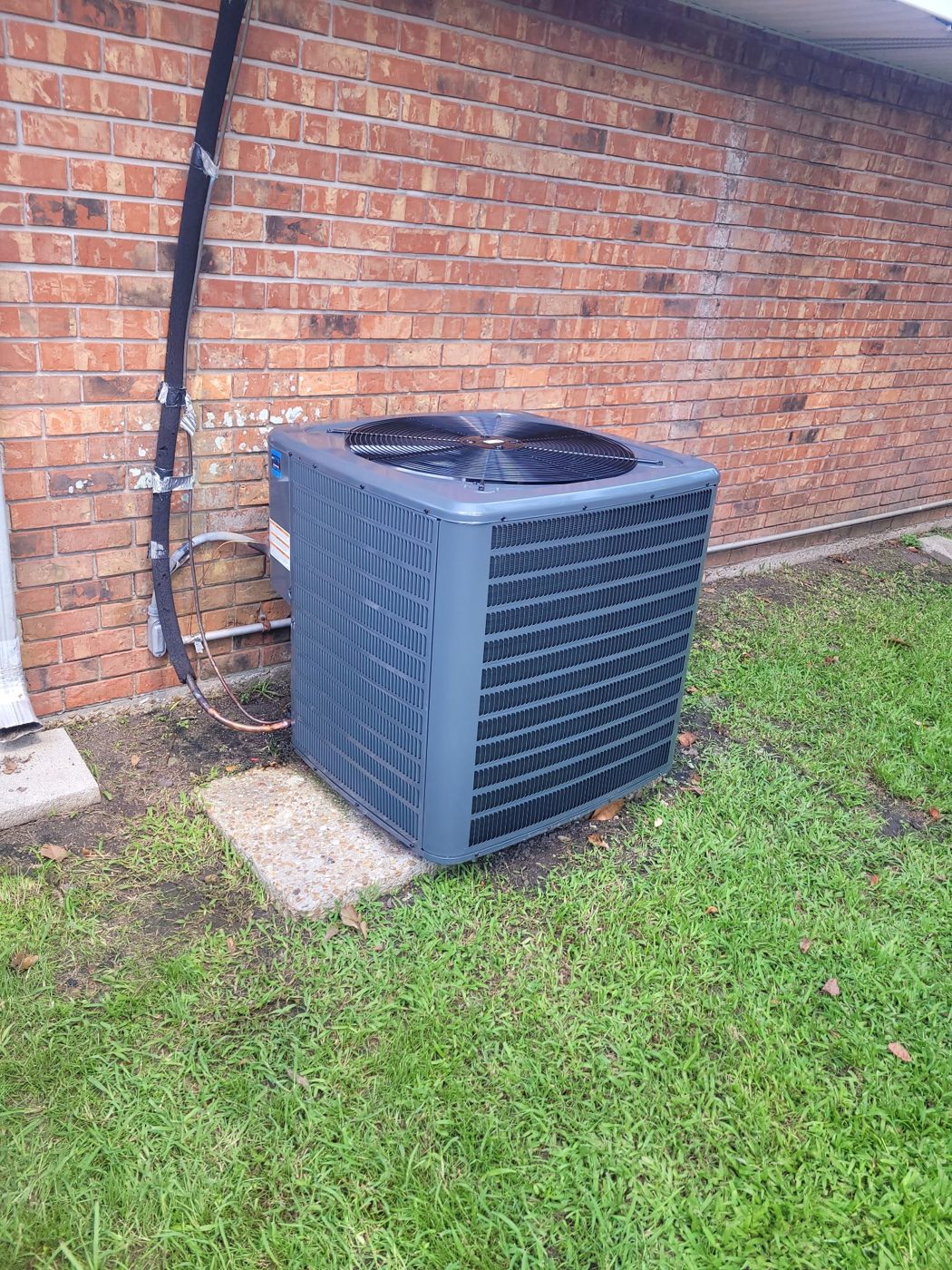 New condenser installed beside a brick home